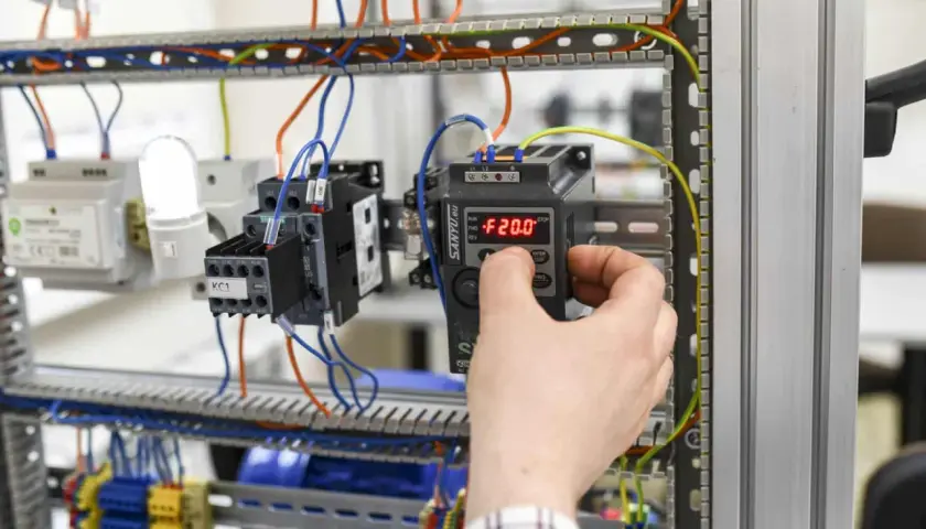 Ręka reguluje panel sterowania w szafie elektrycznej. Zastanawiasz się, ile zarabia magister inżynier elektryk?