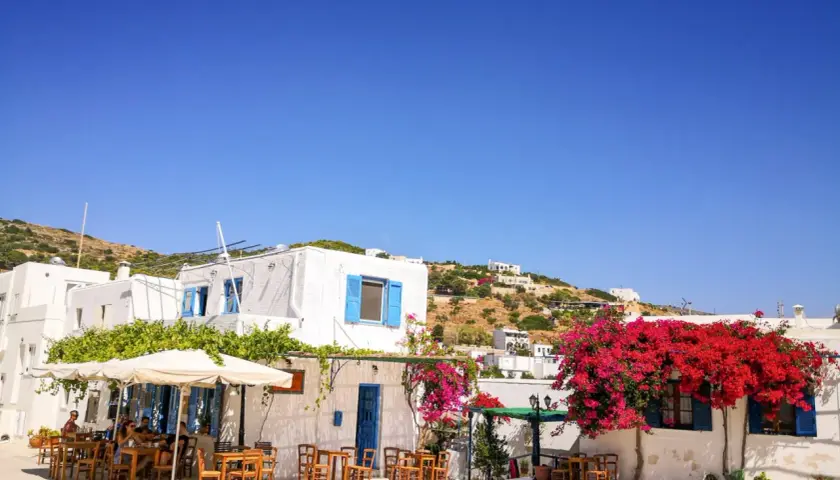 Un angolo di **Grecia con bambini** che giocano felici tra i tavolini di un caffè, sotto bouganville fiorite e il cielo azzurro.