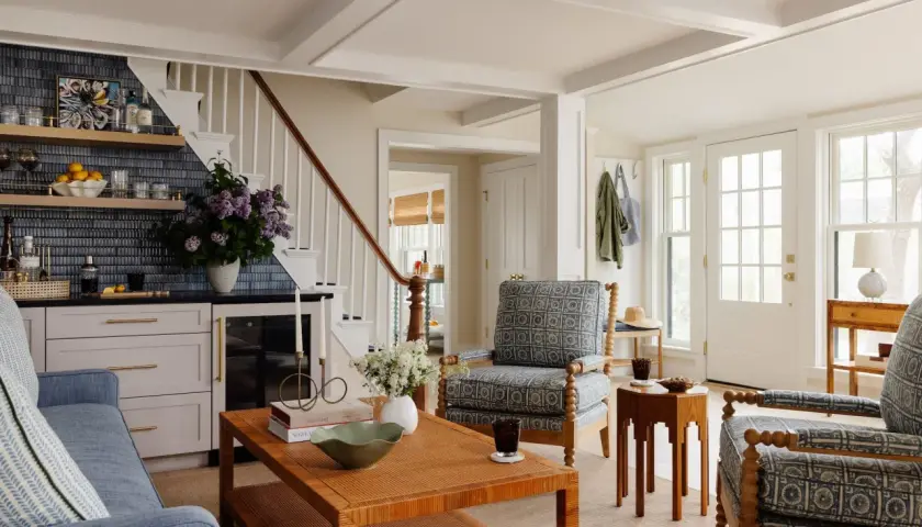 Cozy living room with blue sofa, patterned armchairs, and a rattan coffee table, offering charming farmhouse furniture ideas.