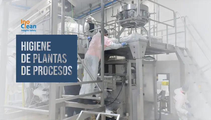 Trabajadores con trajes protectores limpian maquinaria industrial. La asepsia que es, se aplica para garantizar la higiene en plantas de procesos.