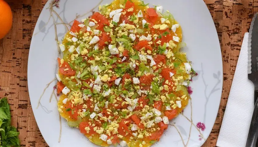 Deliciosa ensalada de invierno con rodajas de naranja, tomate picado, huevo duro y perejil fresco.