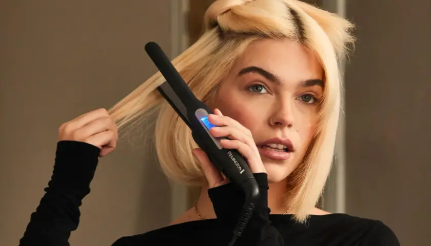 Blondynka używa prostownicy Remington, by nadać objętość włosom u nasady.