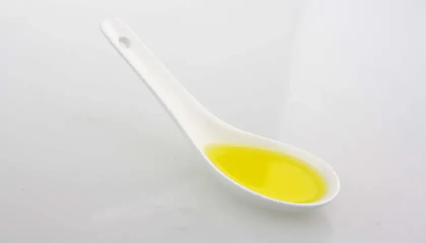 Ein Löffel mit goldenem Olivenöl. Achten Sie auf die Olivenöl Kalorien, wenn Sie es genießen.