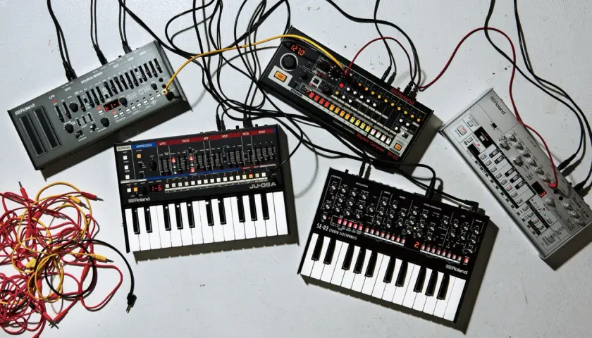 Ensemble de matériel pour composer musique électronique : synthétiseurs, boîtes à rythmes et câbles.