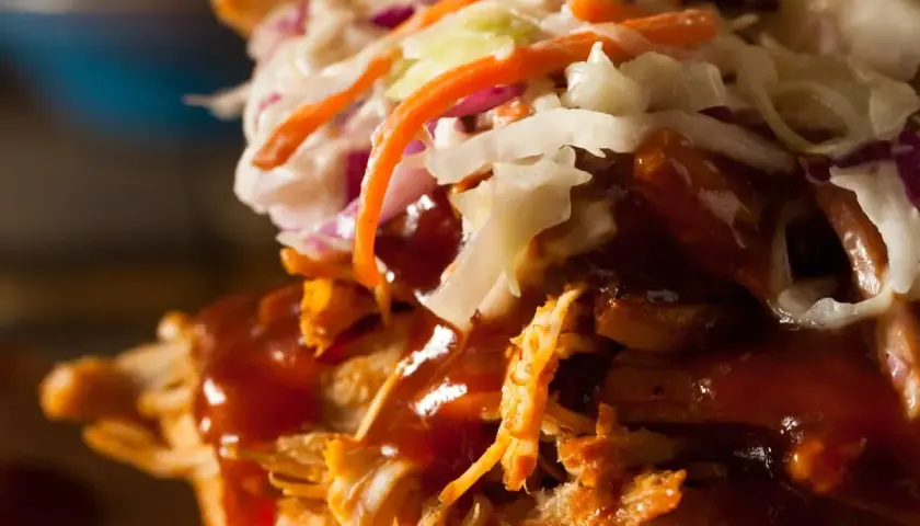 Gros plan sur un sandwich gourmand : effiloché de porc savoureux, sauce barbecue onctueuse et salade de chou croquante. Un délice !