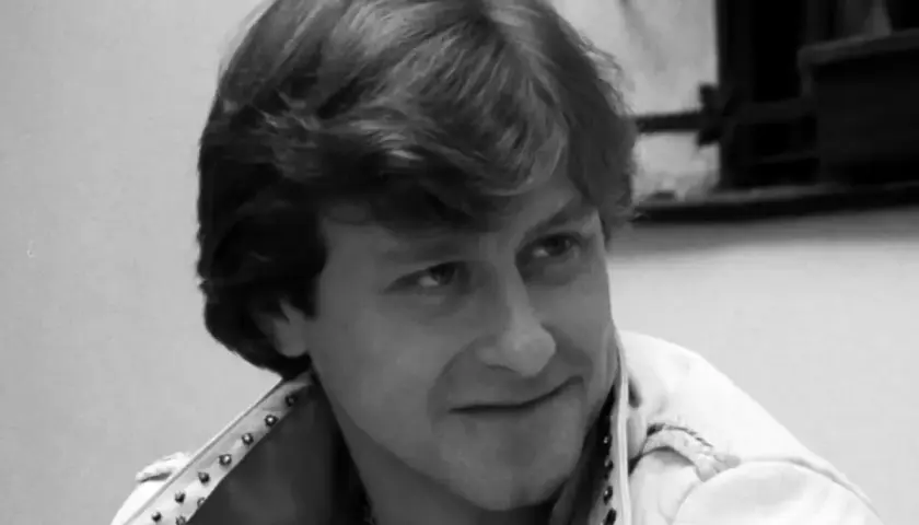 Uśmiechnięty mężczyzna w skórzanej kurtce z ćwiekami, kadr z filmu "Tulipan".