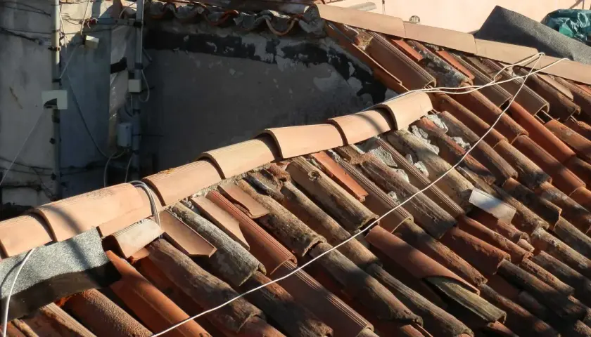 Dettaglio di un vecchio tetto con tegole in terracotta danneggiate, un esempio di come sistemare un vecchio tetto per ripristinarne l'integrità.