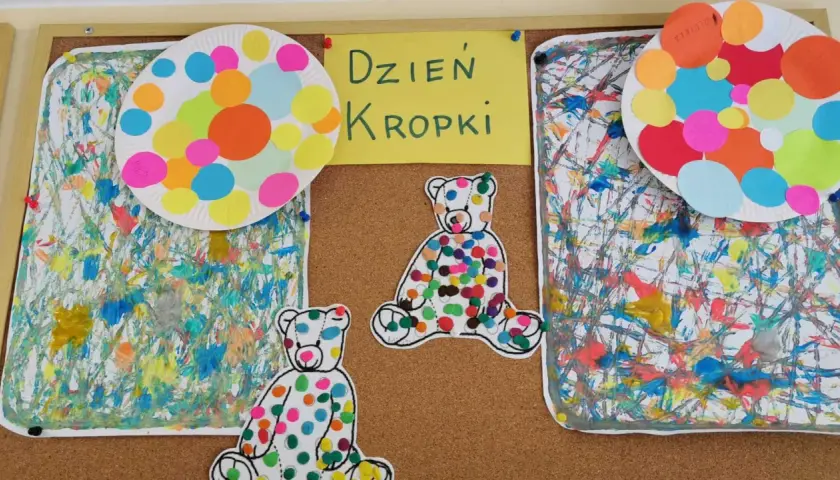 Kolorowe misie i talerzyki z kropkami ozdabiają tablicę z napisem "Dzień Kropki". Prace plastyczne pełne radości i barw.