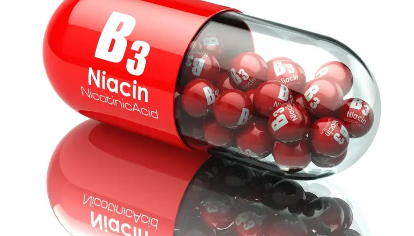 Czerwona kapsułka z witaminą B3 (niacyna) wypełniona małymi, czerwonymi kulkami z napisem "Niacin B3".