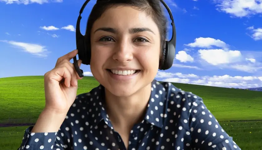 Uśmiechnięta kobieta w słuchawkach z mikrofonem, z klasycznym tłem "Bliss" z Windows XP. Dowiedz się, jak ustawić tło w Teams, by Twoje rozmowy były przyjemniejsze!