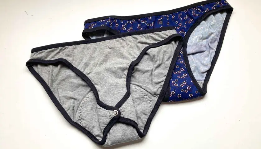 Two pairs of cotton underwear, one grey with a snap closure, the other blue floral. Perfect for a DIY period underwear project.