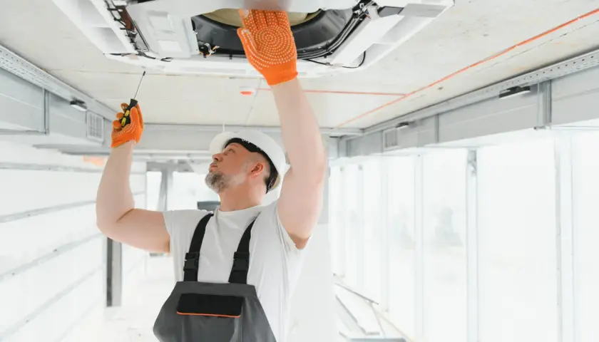 Técnico revisa unidad de aire acondicionado en el techo. Aprende como saber si un aire acondicionado tiene gas.