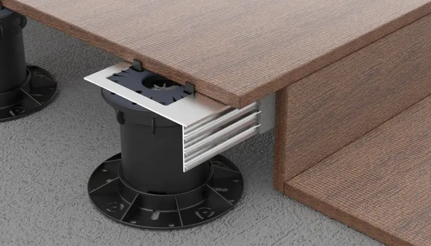 Dettaglio di un pavimento appoggiato su supporti regolabili neri, con finitura effetto legno marrone e profili metallici.