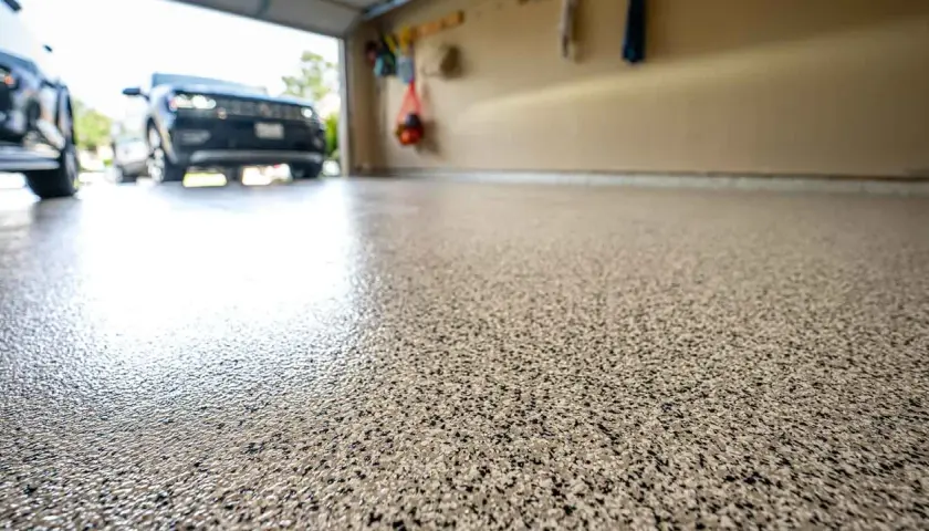 Glänzender, gesprenkelter garagenboden beschichten. Autos parken auf dem frisch beschichteten Boden.