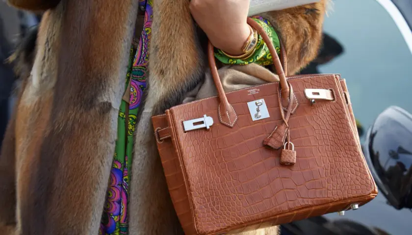 Elegancka torebka marki Hermes w kolorze koniaku, wykonana ze skóry krokodyla, z charakterystycznym zapięciem i małą kłódką.