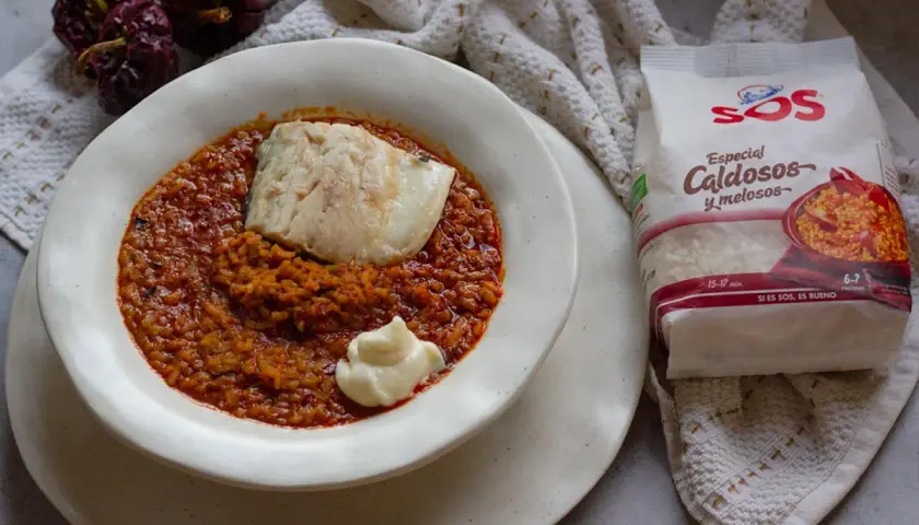 Un plato de caldero murciano con pescado y un toque de alioli, acompañado de arroz especial caldoso y pimientos secos.