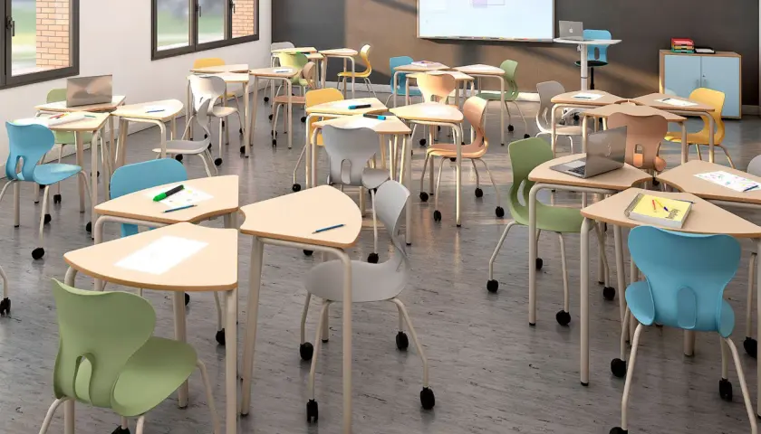 Aula moderna con mobiliario escolar innovador: mesas triangulares y sillas ergonómicas de colores vibrantes, listas para el aprendizaje.