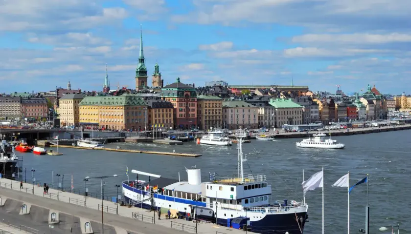 Widok na port w Sztokholmie, gdzie cumuje prom. W tle kolorowe kamienice i wieże.