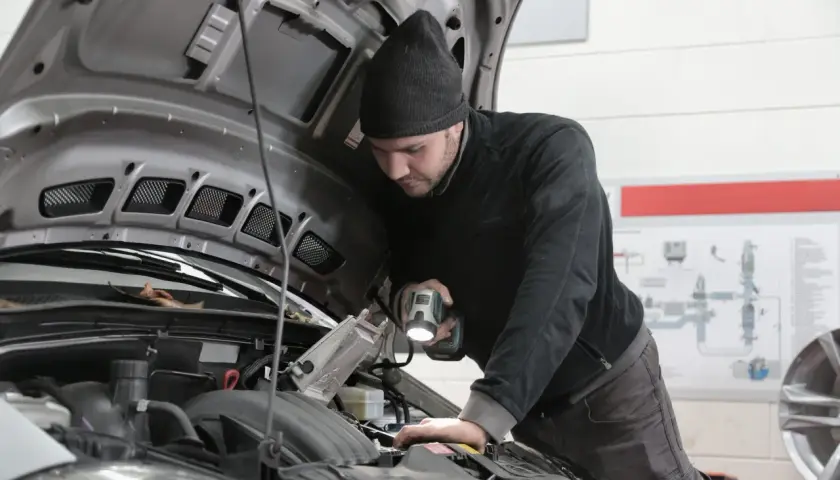 Mechanik sprawdza silnik, szukając przyczyny awarii. Zastanawiasz się, ile kosztuje naprawa silnika w samochodzie?