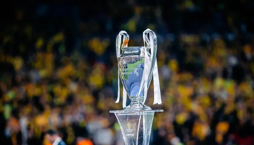 Trofeum Ligi Mistrzów na tle rozmazanej publiczności. Wartość awansu do Ligi Mistrzów jest ogromna.
