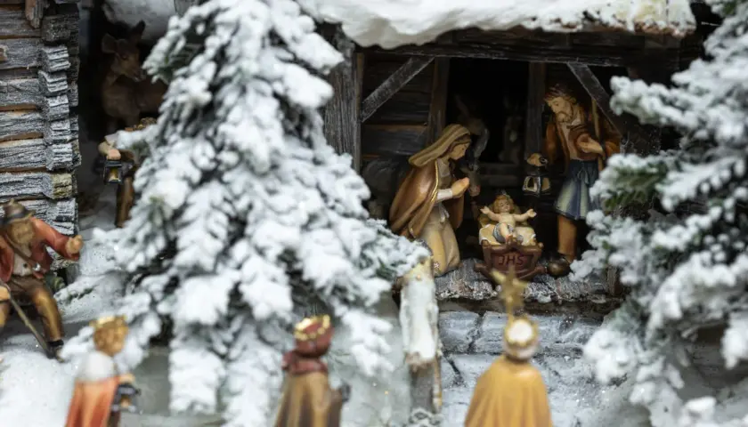 Winterliche Krippenszene mit Maria, Josef und dem Jesuskind. Hirten und Könige nähern sich der Stallung. Ein Sinnbild für Weihnachten und das Christentum.