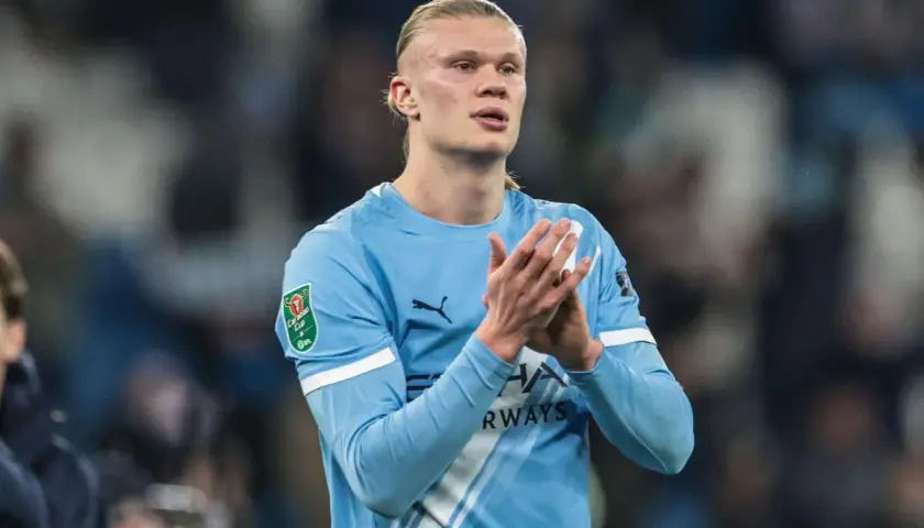 Erling Haaland w błękitnej koszulce Manchesteru City klaszcze, patrząc w bok.