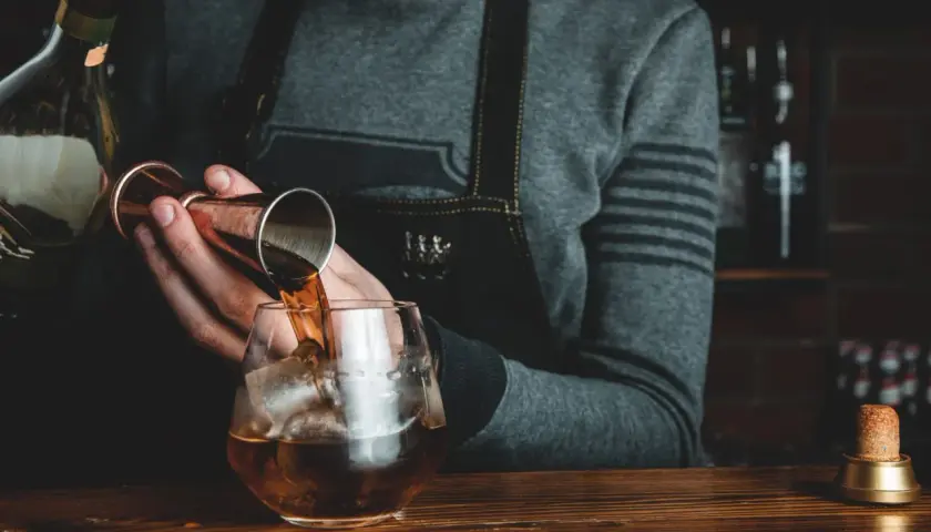 Barman nalewa whisky Glenlivet 12 do szklanki z lodem. Wiele pozytywnych opinii potwierdza jej jakość.
