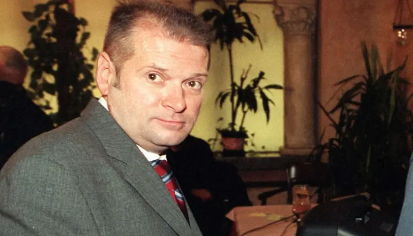 Krzysztof Rutkowski młody, w szarym garniturze i czerwono-niebieskim krawacie, patrzy w obiektyw.