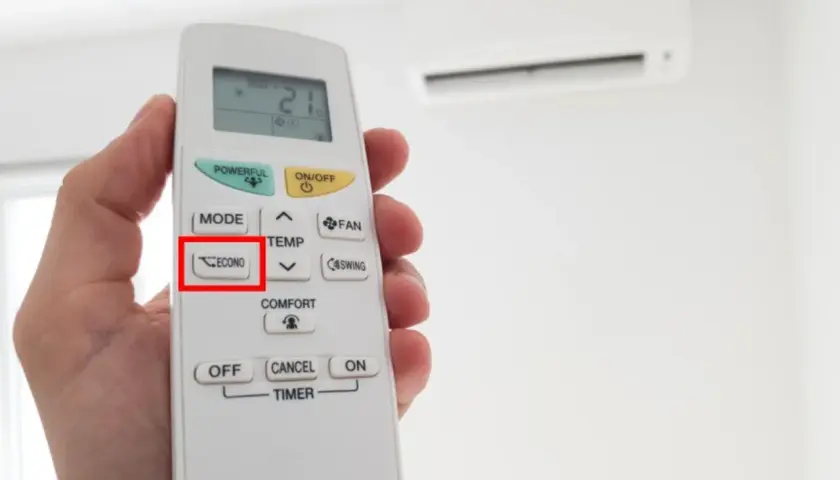 Mano sosteniendo un control remoto de aire acondicionado, con el botón "ECONO" resaltado. Activa el modo eco para ahorrar energía.
