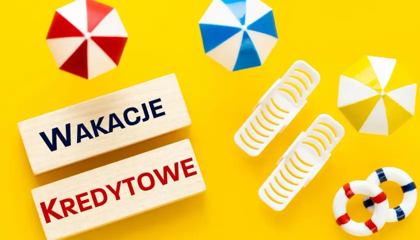 Drewniane klocki z napisem "WAKACJE KREDYTOWE" na tle letnich akcesoriów. Planujesz wakacje kredytowe 2026?