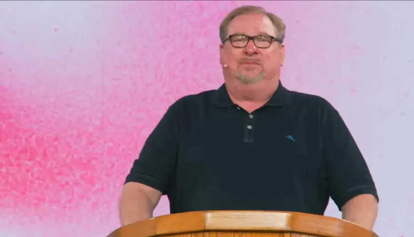 Rick Warren, mit Brille und Bart, spricht hinter einem Holzpult. Der Hintergrund ist pink.