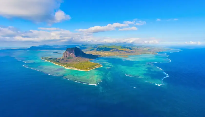Widok z lotu ptaka na Mauritius, gdzie turkusowe wody oceanu otaczają zieloną wyspę z charakterystyczną górą Le Morne Brabant. Nawet podczas pora deszczowa, krajobraz zachwyca.