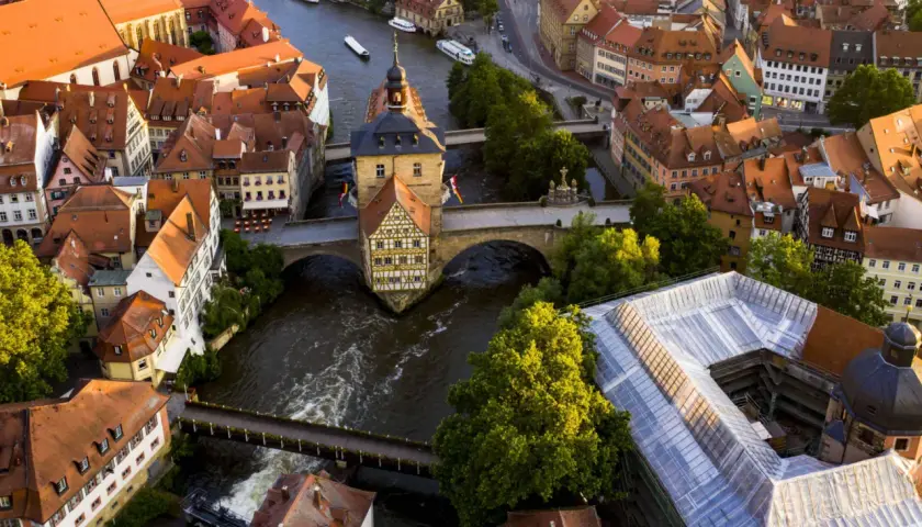 Luftaufnahme von Bamberg: Das Alte Rathaus thront über dem Fluss, umgeben von roten Dächern. Ein perfekter Ort für einen Bamberg Tagesausflug.