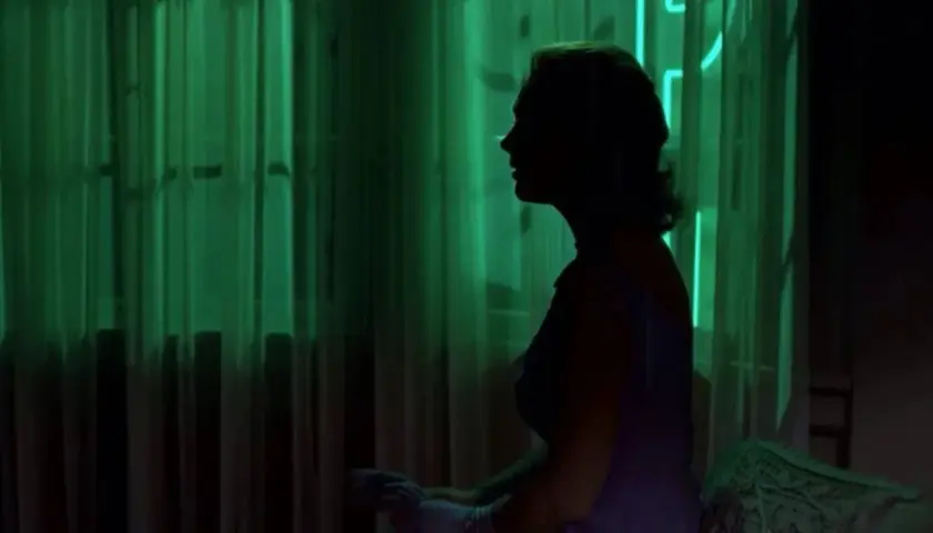 Silueta de mujer en perfil, con cortinas verdes y veo sombras negras que se mueven.