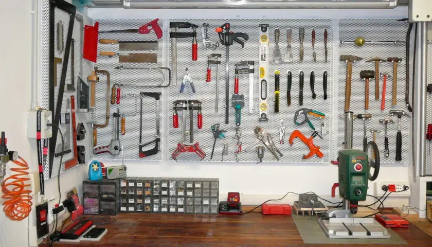 Parete porta attrezzi con pallet, organizzata con martelli, seghe, pinze e altri strumenti.