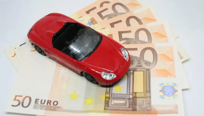 Macchinina rossa su banconote da 50 euro, simbolo di un possibile pignoramento auto cointestata.