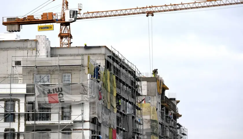 Budowa bloku mieszkalnego z dźwigiem. Pracownicy na rusztowaniach. Ciekawe, ile zarabia deweloper, który to wszystko nadzoruje.