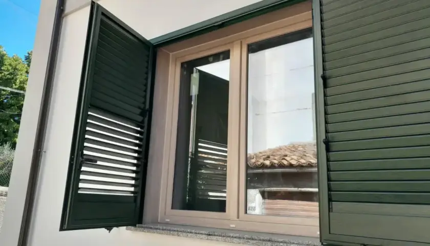 Infissi PVC effetto legno, colori naturali per un'estetica calda e moderna. Le persiane verdi si integrano perfettamente.