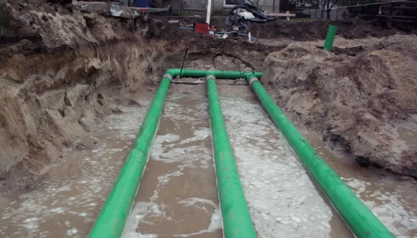 Instalacja gruntowego wymiennika ciepła w wykopie z zielonymi rurami.