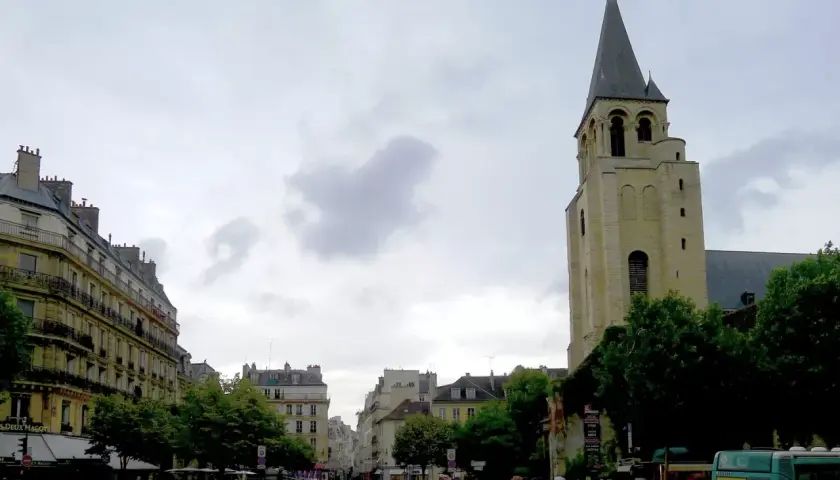 Wieża kościoła Saint-Germain-des-Prés na tle paryskiej ulicy z budynkami i przechodniami.