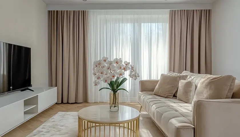 Elegancki salon z zasłonami na karniszu sufitowym z maskownicą, jasną kanapą i stolikiem kawowym.
