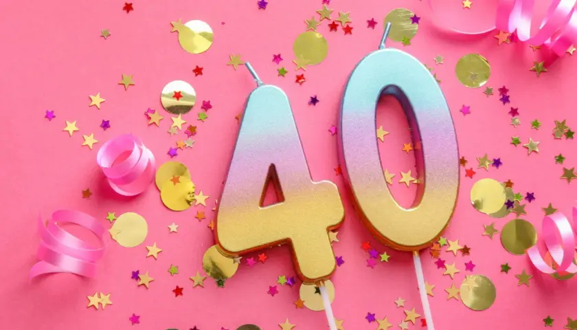Velas con el número 40, confeti de estrellas y círculos dorados, y cintas rosas sobre fondo rosa. ¡Perfecto para frases 40 cumpleaños originales!