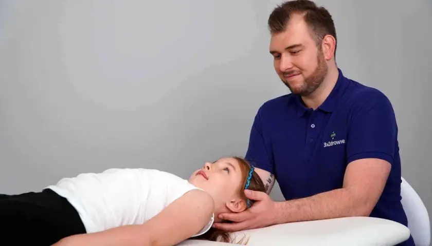 Terapia czaszkowo-krzyżowa pomaga dziecku z depresją. Terapeuta delikatnie dotyka głowy dziewczynki.