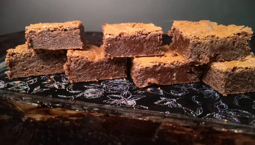 En hög med saftiga chokladbrownies på en glittrig svart bricka. Perfekt för en fika!