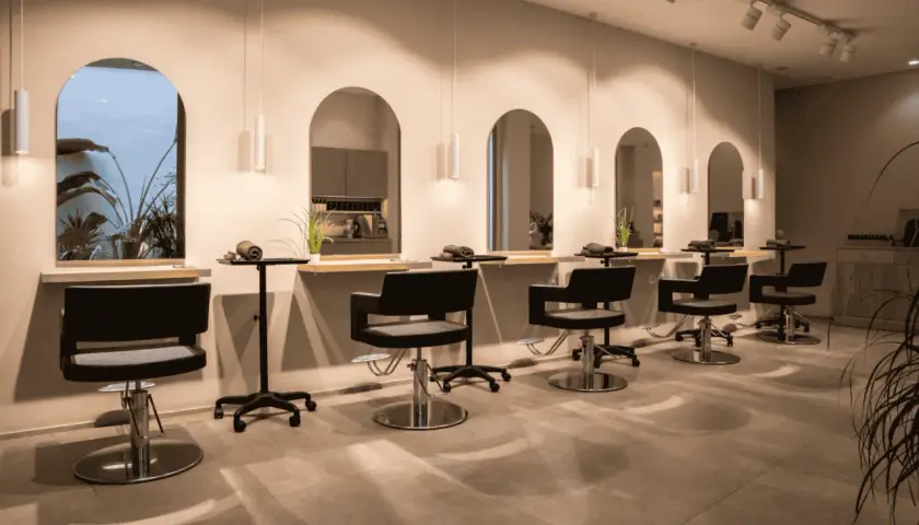 Estilo moderno en peluquería. Sillones negros, espejos arqueados y plantas. Descubre los secretos de agua peluquería para un look radiante.