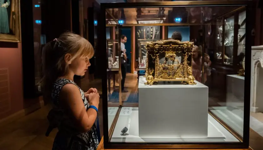 Dziewczynka z zaciekawieniem ogląda złoty, zabytkowy przedmiot w gablocie w muzeum Czartoryskich.