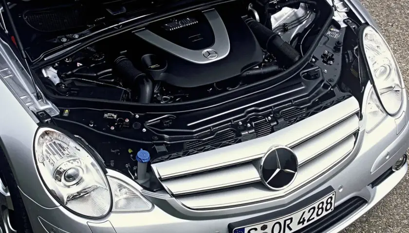 Motor de Mercedes Clase R, con capó abierto. Se aprecian componentes mecánicos y el logo de Mercedes. Posibles mercedes clase r problemas.