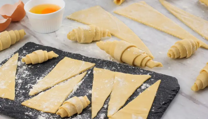 Ingredientes para la receta de cruasanes: masa enrollada, huevos batidos y cáscaras de huevo.