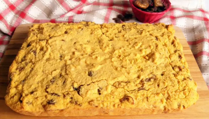 Pincia veneziana, dolce tipico natalizio, con uvetta e fichi secchi, su tagliere di legno.