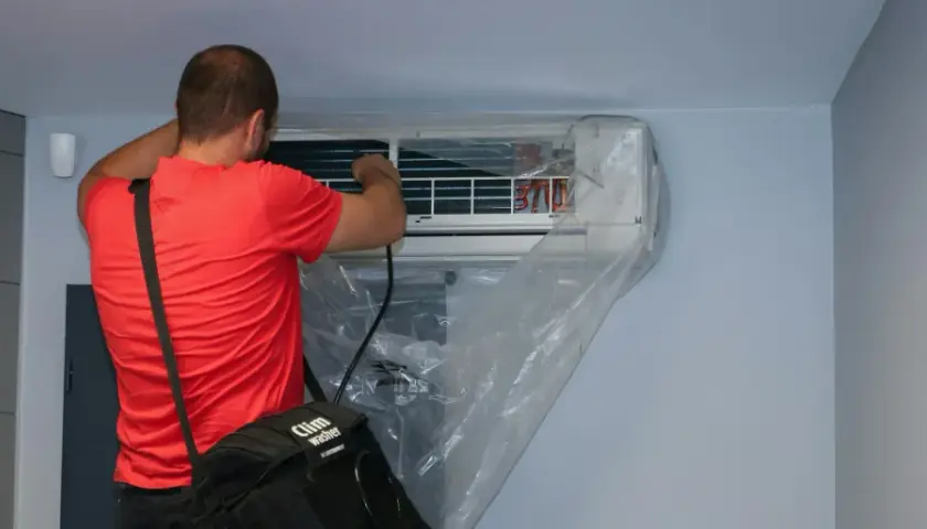 Un technicien effectue l'entretien d'une climatisation murale, une tâche essentielle pour tout locataire ou propriétaire soucieux de son confort.